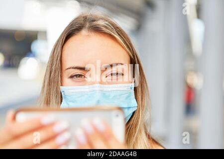 Junge Frau mit Maske wegen Covid-19 Pandemie nimmt ein Selfie im Stadtzentrum Stockfoto