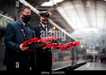 Militärangehörige tragen Mohnkränze am Bahnhof Paddington in London für „Mohnblumen nach Paddington“, der Gedenkkränze aus ganz Großbritannien mit der Great Western Railway nach London Paddington transportiert. Kränze werden um das Kriegsdenkmal der Station für die zwei Minuten Stille gelegt, um an die Kriegtot am Waffenstillstandstag zu erinnern. Stockfoto