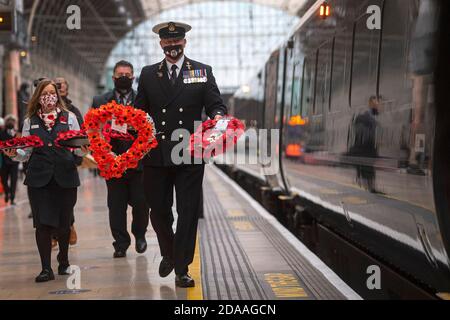 Militärangehörige tragen Mohnkränze am Bahnhof Paddington in London für „Mohnblumen nach Paddington“, der Gedenkkränze aus ganz Großbritannien mit der Great Western Railway nach London Paddington transportiert. Kränze werden um das Kriegsdenkmal der Station für die zwei Minuten Stille gelegt, um an die Kriegtot am Waffenstillstandstag zu erinnern. Stockfoto