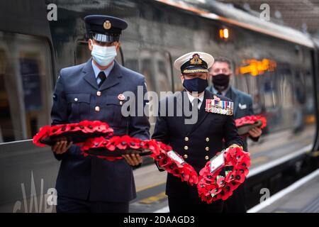 Militärangehörige tragen Mohnkränze am Bahnhof Paddington in London für „Mohnblumen nach Paddington“, der Gedenkkränze aus ganz Großbritannien mit der Great Western Railway nach London Paddington transportiert. Kränze werden um das Kriegsdenkmal der Station für die zwei Minuten Stille gelegt, um an die Kriegtot am Waffenstillstandstag zu erinnern. Stockfoto