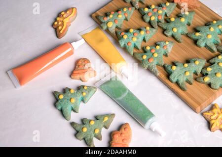 Malen und fertig bemalte Weihnachten Lebkuchen Cookies auf dem weißen Hintergrund der Tischdecke. Nahaufnahme, Kopierbereich. Horizontale Ausrichtung Stockfoto