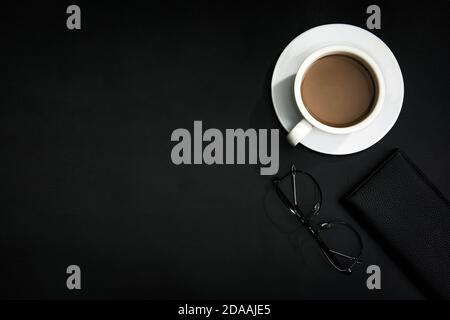 Draufsicht auf eine Tasse Kaffee, Gläser und eine Brieftasche auf einer dunklen Oberfläche Stockfoto