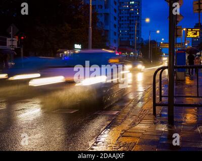 Regnerische Stadtstraße in der Nacht, nächtlicher Verkehr auf nasser Straße bei Regen, Straßenbeleuchtung in Pfützen reflektiert. Stockfoto