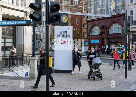 Fußgänger und ein soziales Distanzierungsschild am Oxford Circus im Londoner West End, am Nachmittag des 10. November 2020 Stockfoto