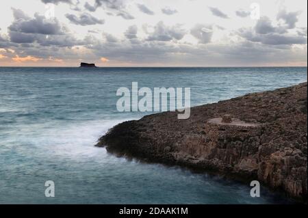 Schöne friedliche romantische Sonnenuntergang in Wiet iz Zurrieq, Malta. Niedrige Verschlusszeit, verschwommenes Meer, kunstvoller Blick auf das Meer Stockfoto