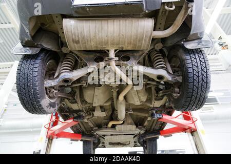 Altes Auto auf dem Lift im Service-Center vor verschwommenem Hintergrund. Ansicht der Hinterradaufhängung des Fahrzeugs. Stockfoto