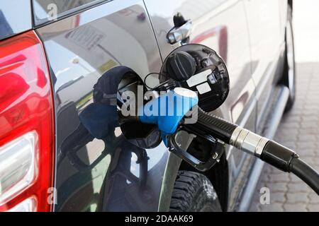 Graues Auto an der Tankstelle wird mit Kraftstoff gefüllt. Nahaufnahme der Tankpistole im Hals des Tanks. Stockfoto