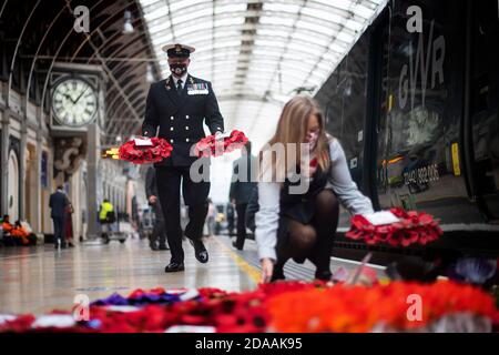 Militärangehörige und ein Mitarbeiter tragen Mohnkränze am Bahnhof Paddington in London, für "Mohnblumen nach Paddington", der Gedenkkränze aus ganz Großbritannien mit der Great Western Railway nach London Paddington transportiert. Kränze werden um das Kriegsdenkmal der Station für die zwei Minuten Stille gelegt, um an die Kriegtot am Waffenstillstandstag zu erinnern. Stockfoto