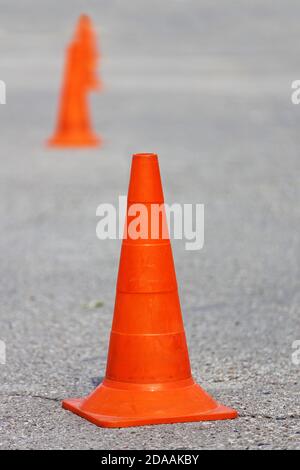 Orangefarbene Plastikkegel auf Asphalt. Geringer Fokus. Stockfoto