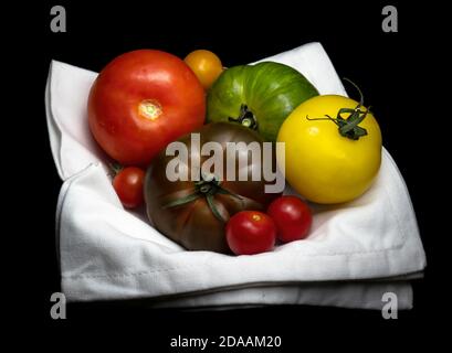 Bunte Tomaten Stillleben auf weißer Serviette, Serviette. Stockfoto