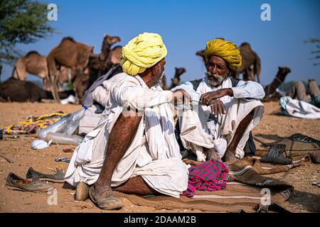 Portrait von zwei Mann in gelb traditionellen Turban diskutieren und sprechen auf pushkar Kamel Festival. Stockfoto