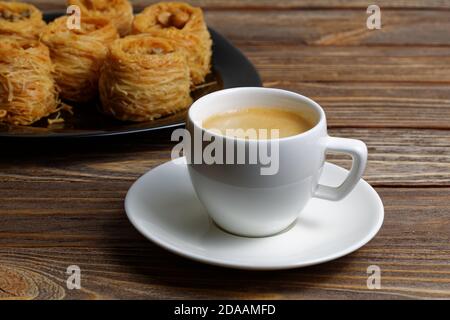 Tasse Kaffee Espresso auf Holztisch und östlichen Süßigkeiten auf verschwommenem Backgrpund. Geringer Fokus. Stockfoto