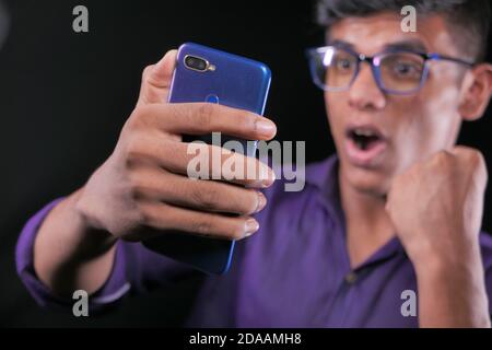 Lächelnder junger Mann in der Brille benutzt sein Telefon Tätigen Sie einen Videoanruf Stockfoto