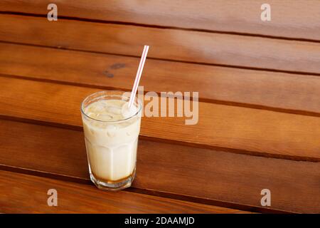 Eiskaffee in einem hohen Glas auf Holztisch. Copyspace. Stockfoto