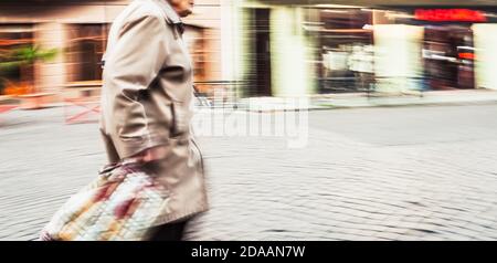 Abstraktes verschwommenes Bild einer alten Frau in der Stadt. Absichtliche Bewegungsunschärfe Stockfoto