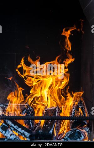 Ein gemauerter, rauchiger Grillofen mit Eisenstangen für Grillspieße mit flammendem Feuer aus verkohlten Holzfeuerhölzern an einem Sommerwochenende im Land Stockfoto