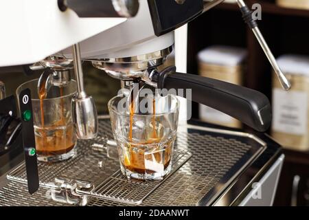 Kaffeebrühen in der Kaffeemaschine. Espressotaffe in Tassen für flachen weißen Kaffee. Geringer Fokus. Stockfoto