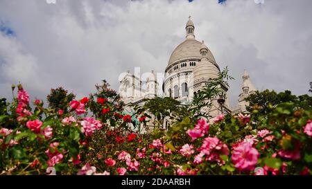 Atemberaubende Basilika des Heiligen Herzens (Sacre-Coeur Basilika) von Paris, Frankreich auf Montmartre Hügel, von unten durch Blumenbeet gesehen. Stockfoto