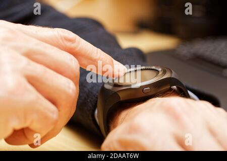 Nahaufnahme Hände von Mann mit seiner Smartwatch. Geringer Fokus. Stockfoto