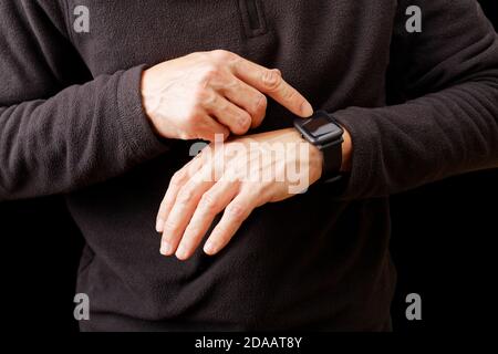 Nahaufnahme Hände von Mann mit seiner Smartwatch. Isoliert auf Schwarz. Stockfoto