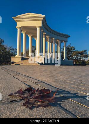 Tschernomorsk, Ukraine 2020. Kolonnade in Tschernomorsk Stadt an einem sonnigen Herbstmorgen mit Ahornblatt. Stockfoto