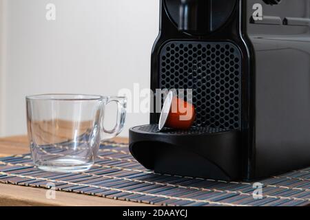 Stillleben von erfrischenden Espresso Kapsel und Tasse neben der Kaffeemaschine innen zu Hause. Niemand Stockfoto