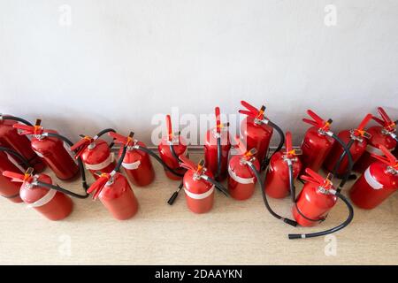 Ein Haufen abgelaufener Feuerlöscher auf dem Boden neben der Wand. Erneuerung der Feuerlöscher für Unternehmen. Stockfoto