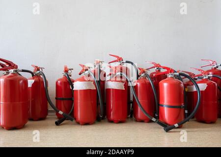 Ein Haufen abgelaufener Feuerlöscher auf dem Boden neben der Wand. Erneuerung der Feuerlöscher für Unternehmen. Stockfoto