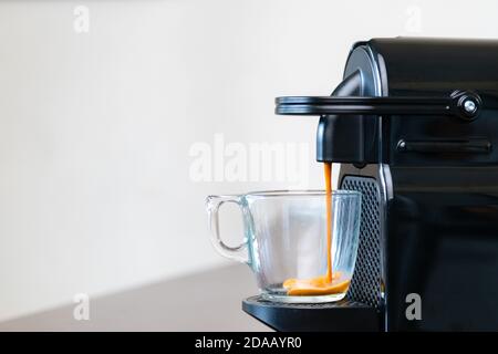 Nahaufnahme von erfrischendem Espresso Gießen der Kapselmaschine in eine Tasse zu Hause. Konzept der Kaffeepause. Stockfoto