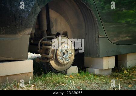 Nahaufnahme des Autos auf Ziegelsteinen draußen. Konzept der gestohlenen Fahrzeugeräder. Auto mit fehlendem Rad. Stockfoto