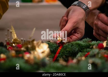 Weihnachten Kranz Weberei. Frau Hände verzieren holiday Wreath der Fichte Äste, Kegel und verschiedenen organischen Dekorationen auf dem Tisch Stockfoto