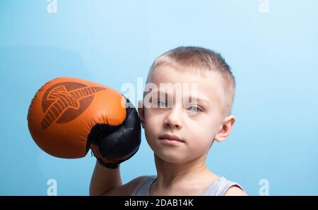 Ein Junge in Boxhandschuhe beschäftigt sich mit Boxen. Das Konzept der gesunden Elternschaft und Sport. Kind auf blauem Hintergrund Stockfoto
