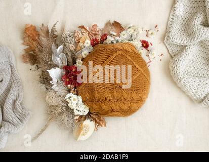 Stillleben im Herbst mit Blumen und gestrickten Elementen auf weißem Hintergrund hautnah. Stockfoto