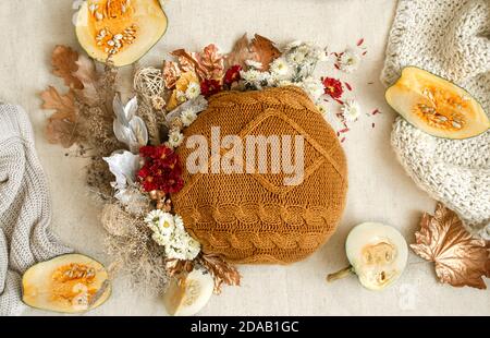 Stillleben im Herbst mit Blumen, Kürbissen und gestrickten Elementen auf weißem Hintergrund hautnah. Stockfoto