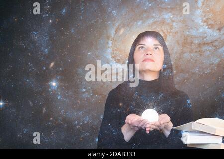 Ein Mädchen mit einem Stern in der Stirn hält einen leuchtenden Ball in den Händen und blickt auf den Sternenhimmel. Das Konzept der paranormalen Fähigkeiten, Hellsehen. Elemente dieses Bildes, die von der NASA eingerichtet wurden. Stockfoto