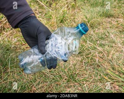 Mann trägt schwarze Einweg-Gummihandschuhe sammeln Plastikflasche (PET) Abfall. Stockfoto