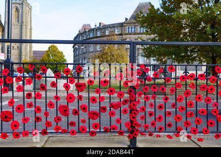 Stahlzaun mit rot gestrickten Mohnblumen für den Remembrance Day im Stadtzentrum von Harrogate, North Yorkshire, England, Großbritannien. Stockfoto