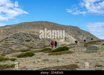 Wanderer und Wanderer, die den Berg an einem sonnigen Tag auf einem Wanderweg besteigen. Aufstieg nach Peñalara in der Sierra de Madrid. Stockfoto
