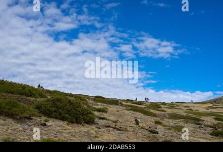 Wanderer, die den Berg an einem sonnigen Tag auf einem Wanderweg besteigen. Aufstieg nach Peñalara in der Sierra de Madrid. Stockfoto
