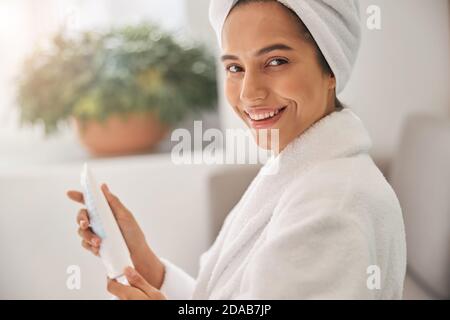 Frau, die die Lotion hält, während sie die Kamera anlächelt Stockfoto