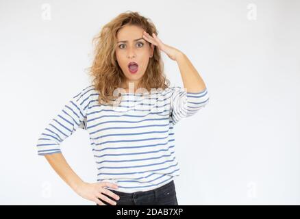 Schöne Frau mit Gesichtsausdruck der Überraschung tragen lässig gestreiften T-Shirt über weißem Hintergrund stehen. Stockfoto