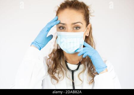 Closed up Porträt der kaukasischen Ärztin trägt OP-Maske auf weißem Hintergrund. Stockfoto