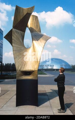 Ein Besucher bewundert die hoch aufragenden Kunstwerke des berühmten Bildhauers Alexander Calder im General Motors Technical Center im Vorort Warren, Michigan, USA. Das modernistische GM Tech Center, das von den international renommierten Vater- und Sohn-Architekten Eliel und Eero Saarinen entworfen wurde, vertrat das industrielle Amerika, als es 1956 mit 25 Gebäuden auf 320 Hektar (130 Hektar) eröffnete. Der vielgelobte Komplex läutete ein neues und neues architektonisches Thema ein: Den Unternehmenscampus, der die Ankunft von Unternehmen als Zentren des Lernens, der wissenschaftlichen Schirmherrschaft und der Macht begrüßte. Stockfoto