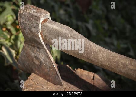 Eine alte rostige Axt mit Holzgriff ist eingeklebt Ein Protokoll Stockfoto