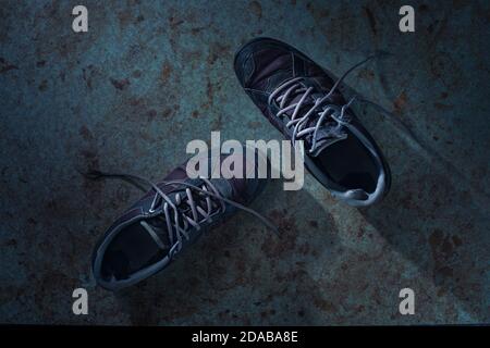 Zwei alte abgenutzte Sneakers auf schmutziger Oberfläche Stockfoto