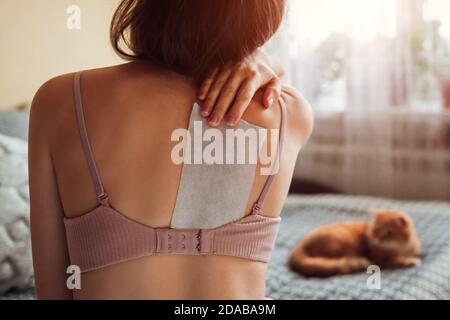 Nahaufnahme des Pflasters zur Linderung von Rückenschmerzen. Frau verachteten Pflaster auf Schulterblatt zu Hause leiden von Rückenschmerzen Stockfoto