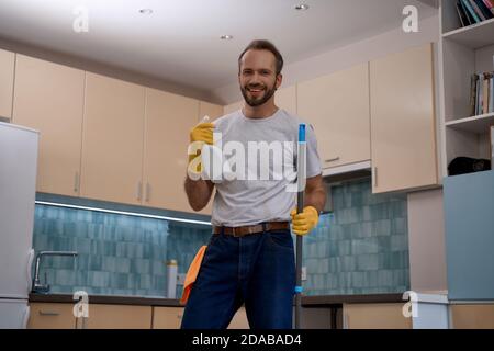 Junger Kaukasier hält Mopp und Waschmittel Sprühflasche Stockfoto