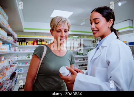 Kaukasische Mutter bekommen Hilfe von gemischten Rasse Apotheker erklärt Dosierung Vorsichtsmaßnahmen für Medikamente Stockfoto