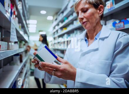 Kaukasische ältere Apotheker Blick auf Rezepte Medikamente Etiketten auf Boxen Für Kunden Stockfoto