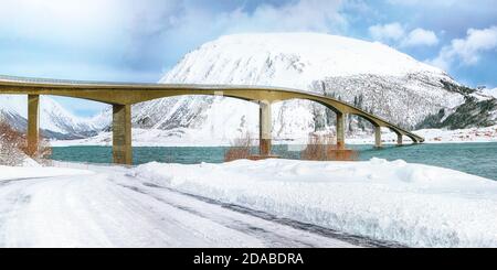 Dramatische Winterszene der Gimsoyststraumen Brücke mit viel Schnee und schneebedeckten Berggipfeln. Lage: Gemeinde Vagan, Landkreis Nordland, Lofotens Stockfoto